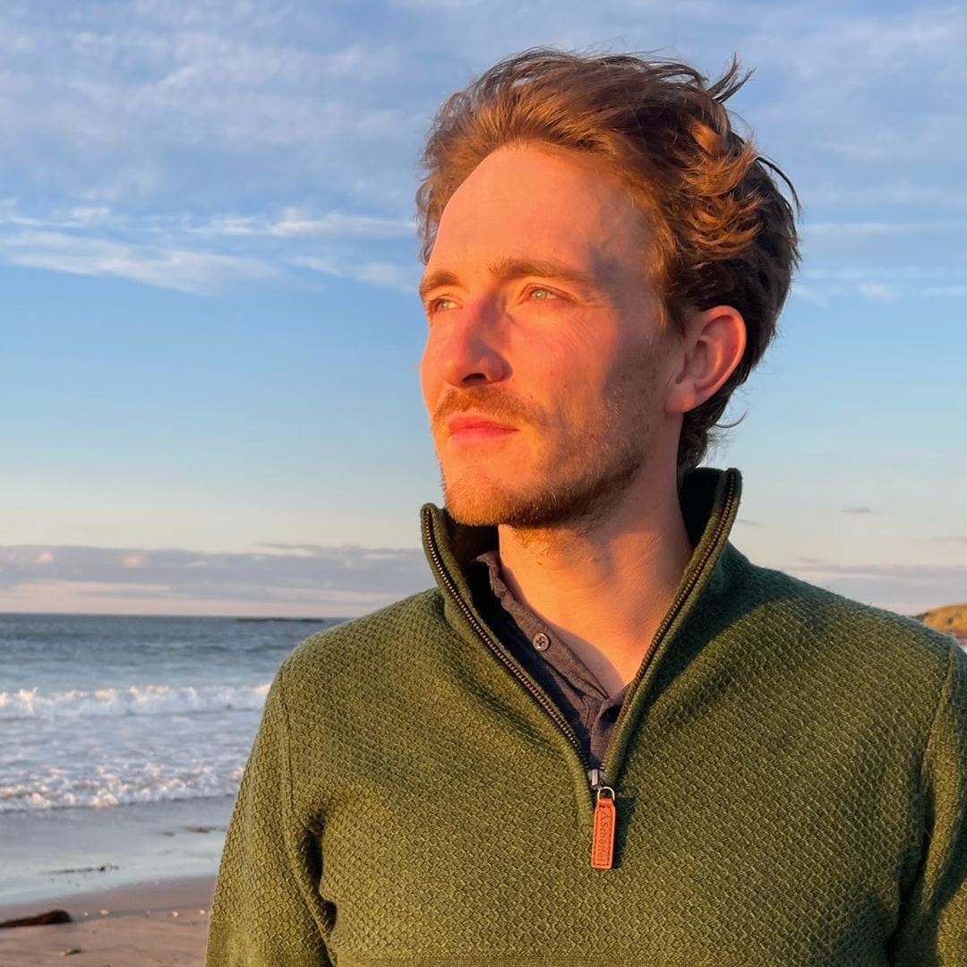 Portret van Ben Arts aan zee, in een groene trui