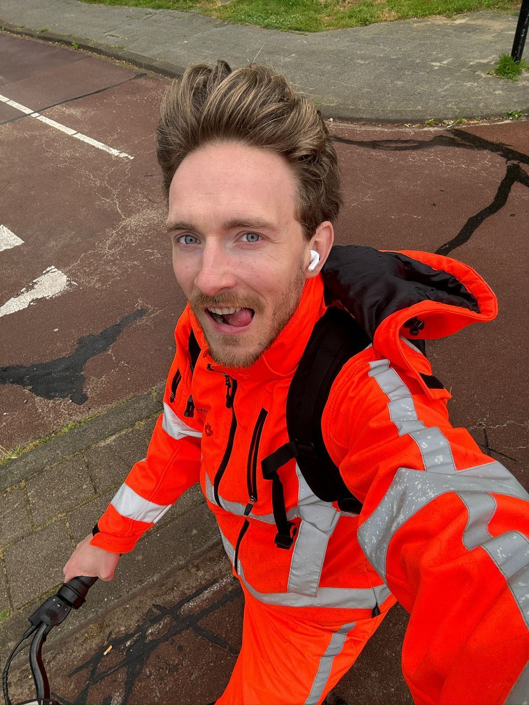Selfie van Ben op de fiets in oranje werkkleding