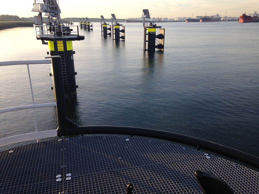 Uitzicht vanaf een stalen loopbrug over het water met meerpalen in de haven